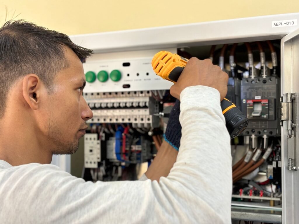 Licensed electrician drilling and mounting a new circuit breaker panel during a panel upgrade in Lincoln, AL