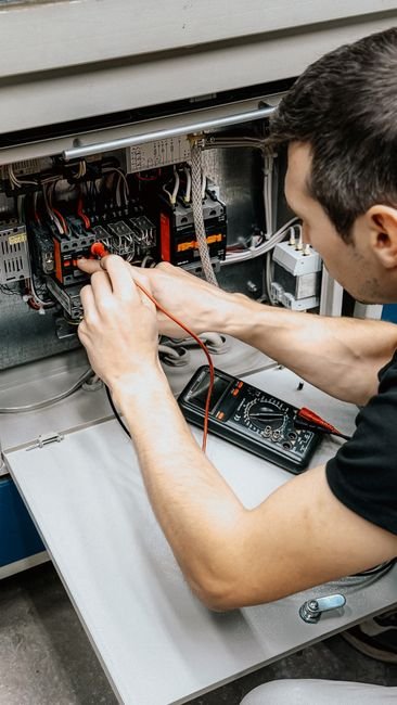 Electrician Testing an Open Electrical Panel with a Multimeter Near Albertville, AL